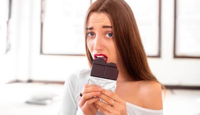 Woman emotionally eating chocolate bar